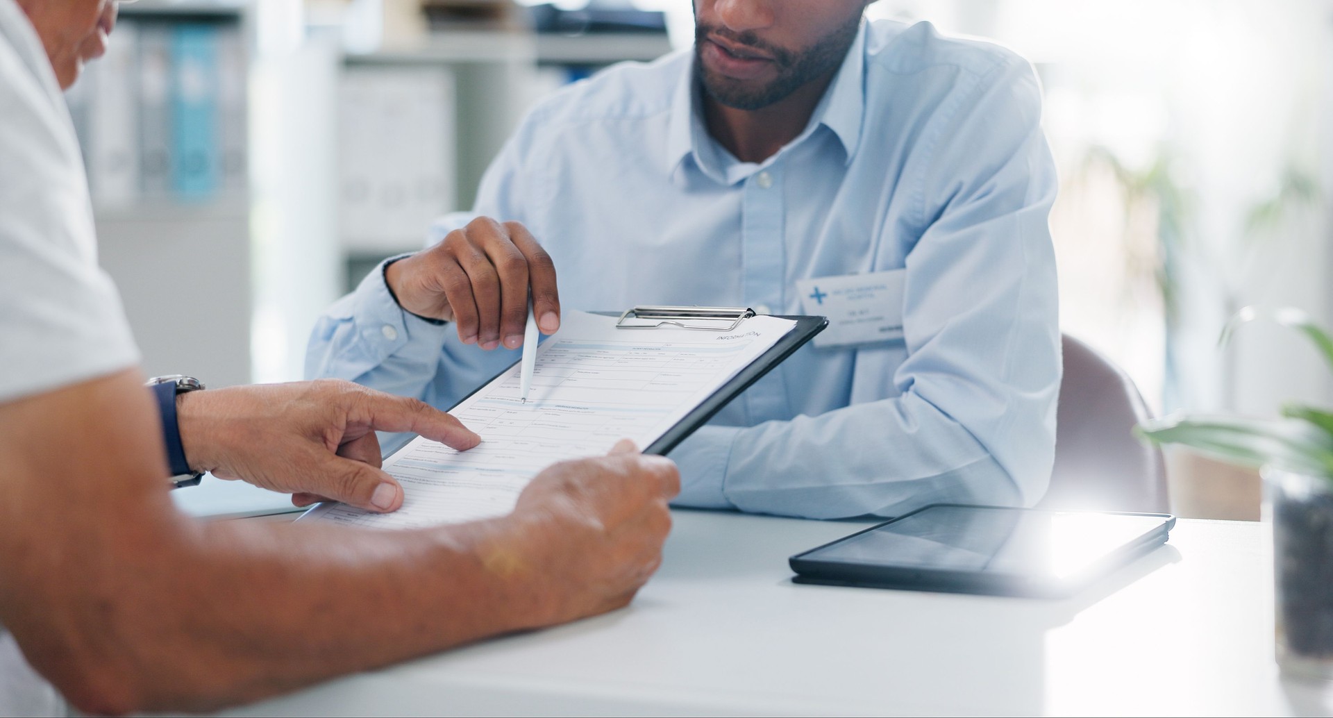 Man, doctor and hands with form in consultation for signature, application or health insurance at hospital. Closeup of person or medical employee explaining document or paperwork to patient at clinic